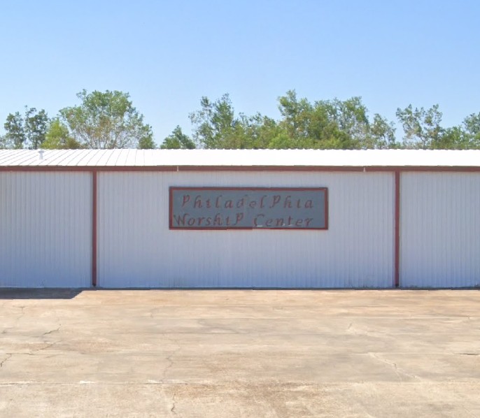 white metal building with red trim and sign that reads, "Philadelphia Worship Center"
