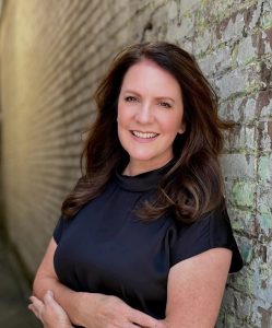 brunette woman leaning against a brick wall