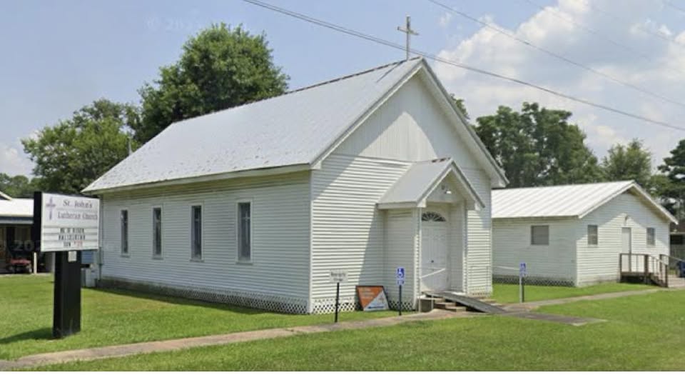 white wood church building with sign to the side
