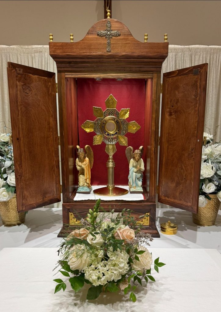 Catholic altar with an open Tabernacle and flowers in front
