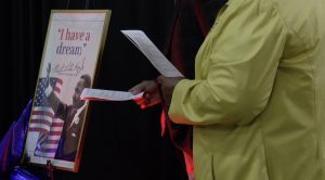 person holding event program with MLK sign in the background