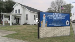 wooden white church with blue sign in front