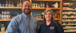 man and woman standing side by side in front of shelves filled with condiments