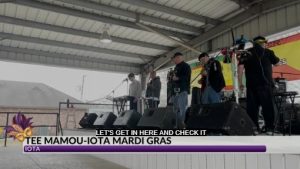 Band playing on stage with news information at the bottom of the screen