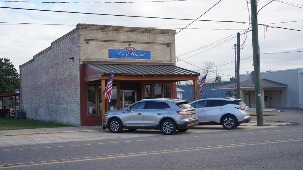Historic, free-standing brick building with front porch and Le Museé sign