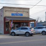 Historic, free-standing brick building with front porch and Le Museé sign