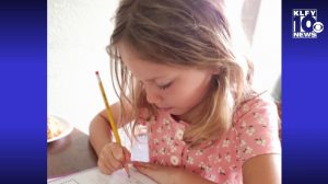 girl writing at a desk with a pencil 