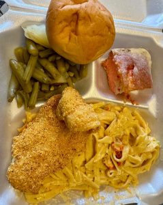 Plate lunch with fettucine, fried fish, sides, and a roll