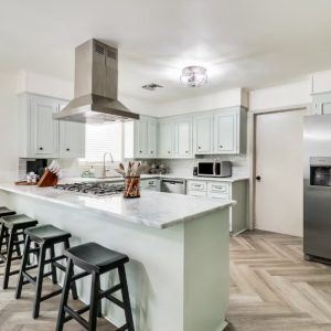 kitchen with mint green cabinets and stainless steel appliances, barstools in the front