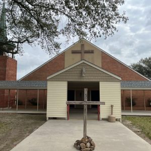 brick church building with wooden cross in front