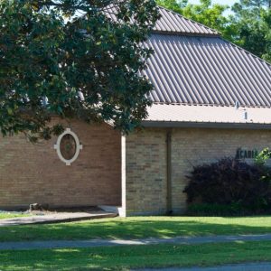 brick building with metal roof and oak tree branch in front of picture