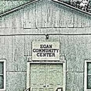 old grayscale picture with a sign on the front of a building reading, "Egan Community Center"