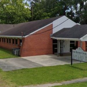 red brick church building with white sign out front