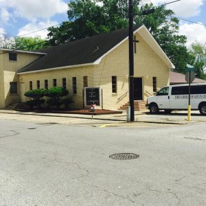 tan-brick church building with white church van outside