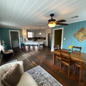 great room with teal walls, couch and dining set in the foreground, kitchen in the far back