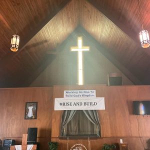 front of church from the inside with light shining through cross-shaped window