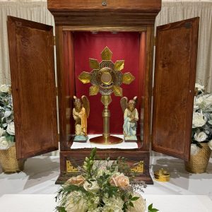 Catholic altar with an open Tabernacle and flowers in front