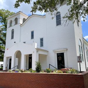 White wooden church building with brick planter out front