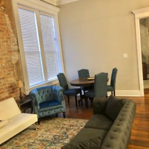 living room with hardwood floors and exposed brick, blue upholstered furniture