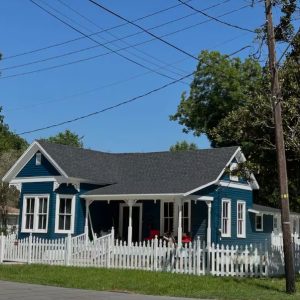 exterior of historic blue home with white trim and white picket fence