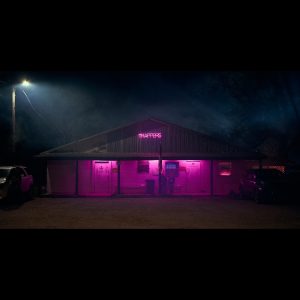 dark picture of Trapper's Bar, lit up in purple neon lights under the porch